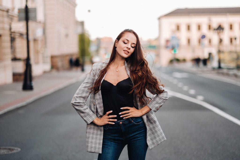 a girl in a jacket and long hair walks through the old city.A beautiful girl smiles.Girl on the road